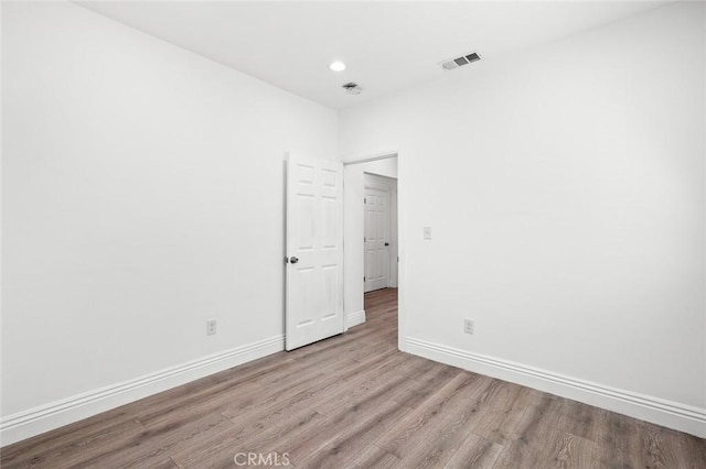 empty room featuring baseboards, visible vents, recessed lighting, and wood finished floors