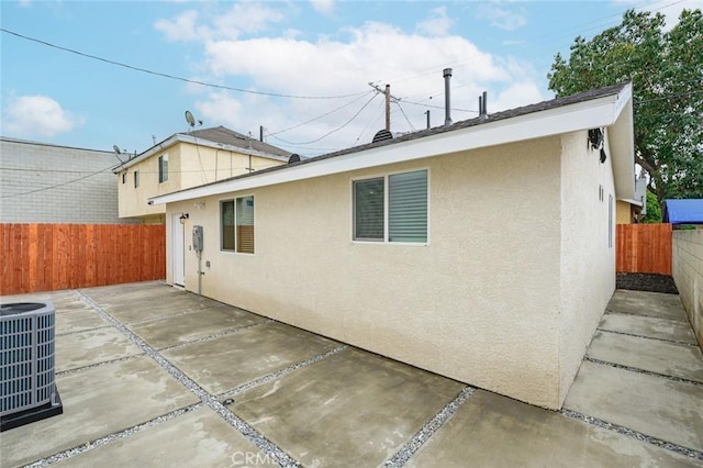 back of property with cooling unit, a fenced backyard, stucco siding, and a patio