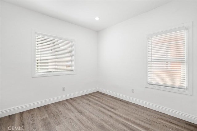 spare room featuring wood finished floors, baseboards, and a wealth of natural light