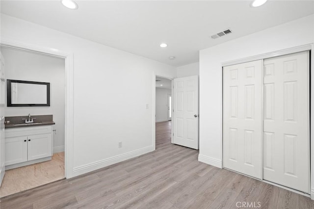 unfurnished bedroom featuring a sink, light wood-style floors, recessed lighting, and visible vents