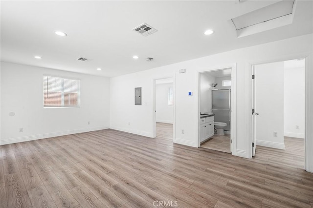 interior space featuring electric panel, attic access, light wood-style flooring, visible vents, and recessed lighting