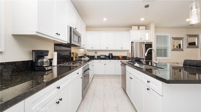 16763 Stags Leap Ln, Fontana, CA 92336 - kitchen featuring appliances with stainless steel finishes, light marble finish flooring, an island with sink, white cabinets, and decorative light fixtures
