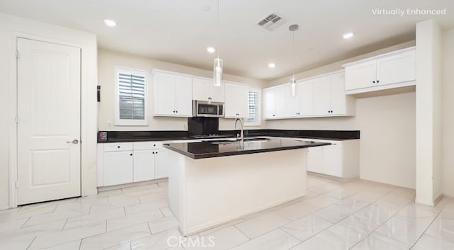16763 Stags Leap Ln, Fontana, CA 92336 - kitchen featuring stainless steel microwave, dark countertops, a center island with sink, white cabinets, and recessed lighting