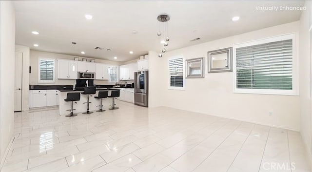 16763 Stags Leap Ln, Fontana, CA 92336 - kitchen featuring stainless steel appliances, dark countertops, a kitchen breakfast bar, white cabinets, and open floor plan