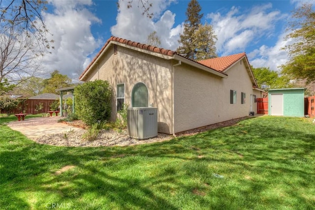 view of side of home featuring a shed, an outdoor structure, stucco siding, and a tiled roof