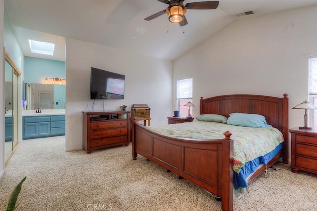 bedroom featuring connected bathroom, visible vents, light carpet, a sink, and lofted ceiling with skylight