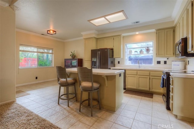 kitchen with visible vents, a center island, a sink, a kitchen bar, and stainless steel appliances