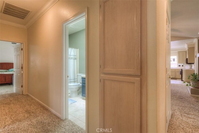 hall with crown molding, visible vents, baseboards, and light colored carpet