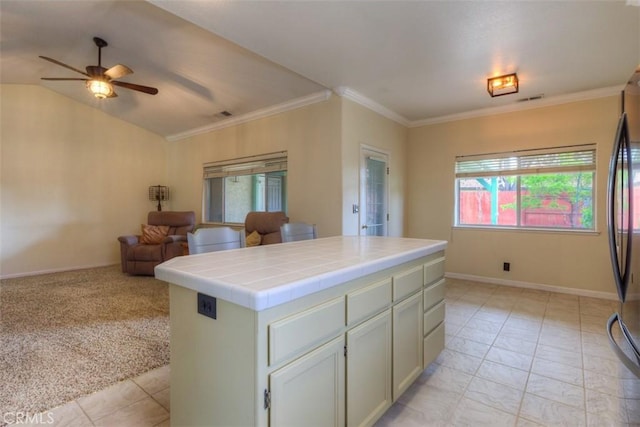 kitchen featuring open floor plan, visible vents, a ceiling fan, crown molding, and tile countertops