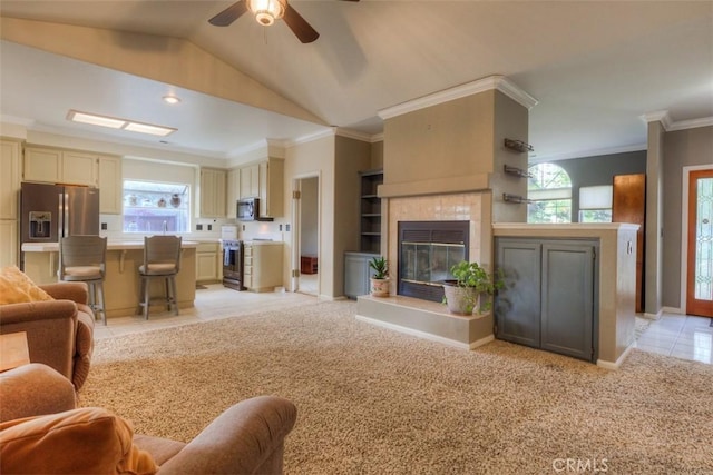 living room featuring crown molding, a fireplace, a ceiling fan, light carpet, and lofted ceiling