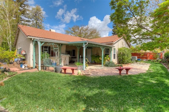 back of house with a patio area, stucco siding, a tile roof, and a lawn