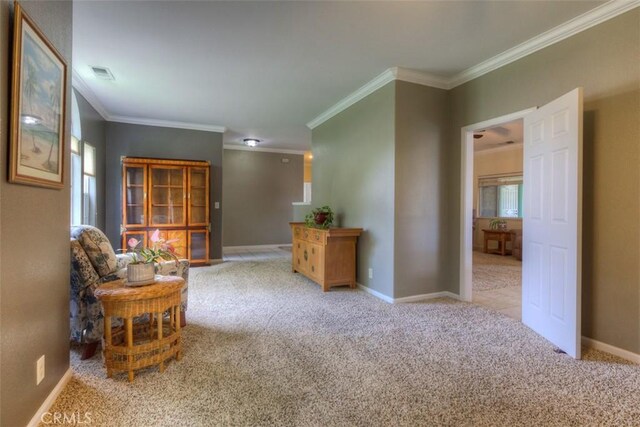 sitting room with carpet flooring, visible vents, and ornamental molding
