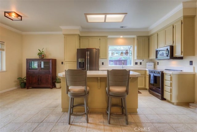 kitchen featuring ornamental molding, appliances with stainless steel finishes, a kitchen island, and cream cabinets