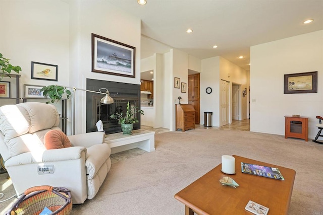 living room featuring light colored carpet, a fireplace with raised hearth, and recessed lighting
