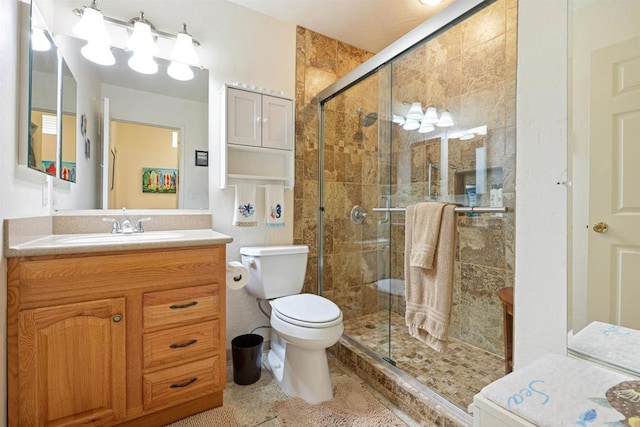 full bathroom featuring a stall shower, toilet, and vanity