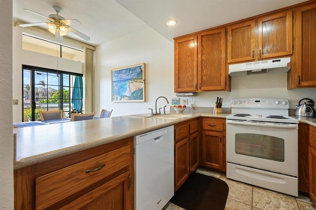 kitchen with white appliances, brown cabinetry, under cabinet range hood, and a sink