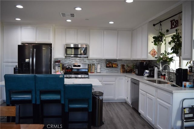 kitchen featuring light countertops, a sink, appliances with stainless steel finishes, visible vents, and white cabinets