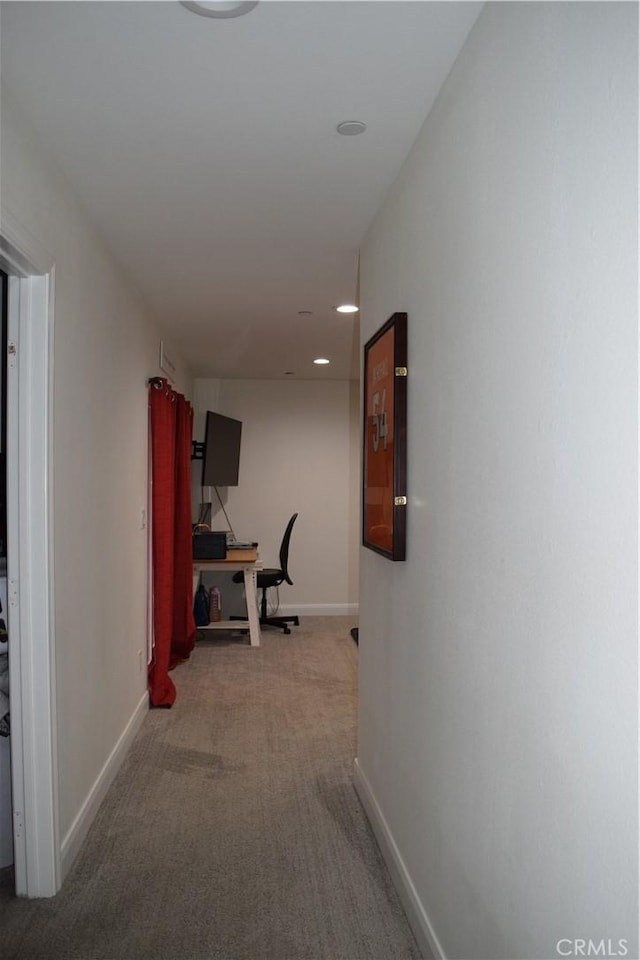 corridor featuring light colored carpet and baseboards
