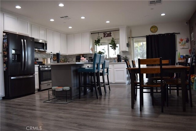 kitchen with white cabinetry, stainless steel appliances, a breakfast bar, and visible vents