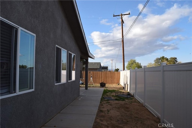 view of side of home with stucco siding and a fenced backyard