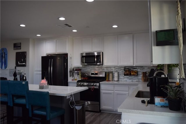 kitchen featuring decorative backsplash, white cabinets, visible vents, and stainless steel appliances