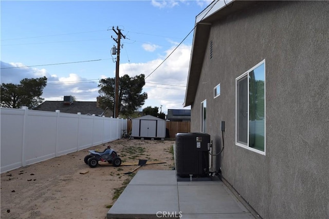 exterior space featuring central air condition unit, stucco siding, an outdoor structure, a storage shed, and a fenced backyard