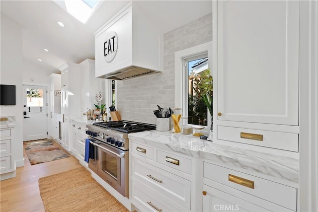 1954 Port Locksleigh Pl, Newport Beach, CA 92660 - kitchen with range with two ovens, white cabinets, backsplash, light stone counters, and a skylight