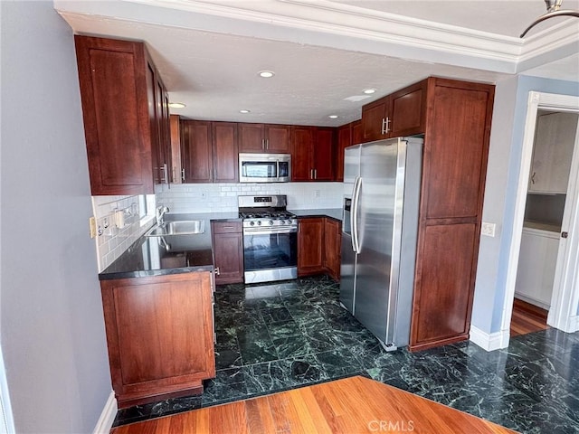 kitchen with decorative backsplash, dark countertops, baseboards, a sink, and appliances with stainless steel finishes
