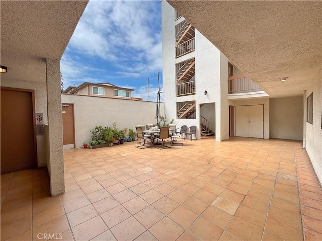 view of patio with fence, outdoor dining space, and stairway