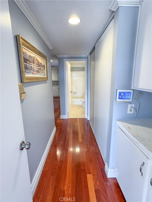corridor featuring crown molding, baseboards, dark wood finished floors, and washer / clothes dryer