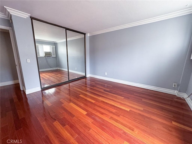 unfurnished bedroom with baseboards, ornamental molding, wood finished floors, and a closet