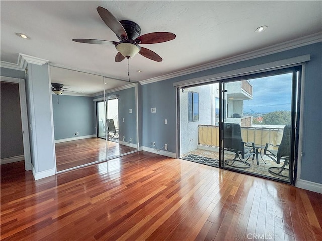 spare room with baseboards, ornamental molding, ceiling fan, and wood finished floors
