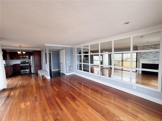 unfurnished living room with baseboards, a chandelier, wood finished floors, and a fireplace