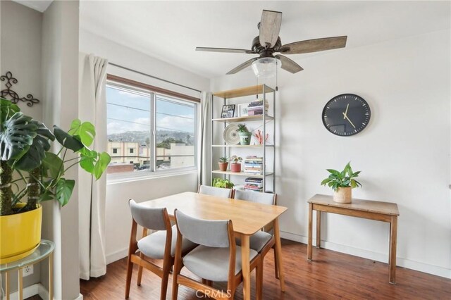 dining room featuring wood finished floors, a ceiling fan, and baseboards
