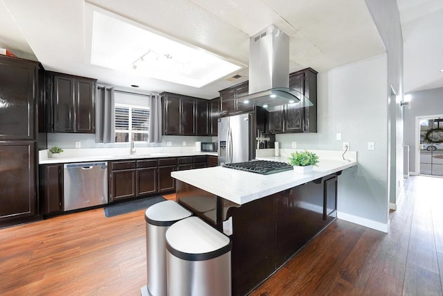 25318 Kerri Ln, Ramona, CA 92065 - kitchen with island exhaust hood, a sink, a peninsula, appliances with stainless steel finishes, and wood finished floors