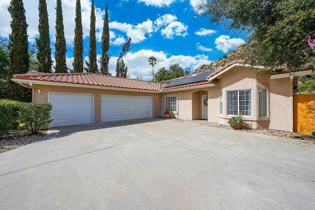 25318 Kerri Ln, Ramona, CA 92065 - ranch-style house featuring stucco siding, an attached garage, a tile roof, and roof mounted solar panels