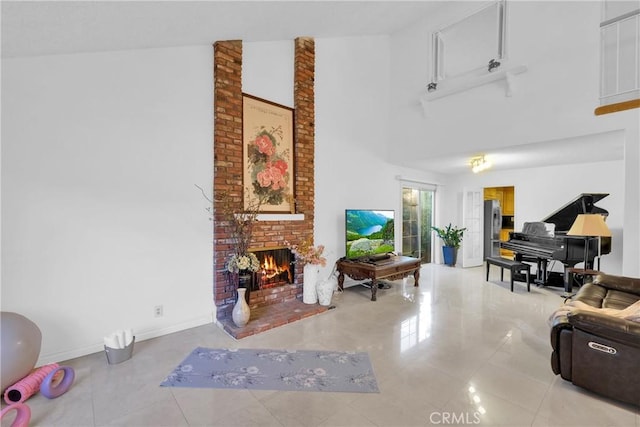 living room with a brick fireplace, a towering ceiling, light tile patterned floors, and baseboards