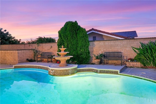 pool at dusk featuring a fenced in pool and a fenced backyard
