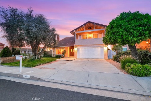 view of front of house featuring concrete driveway, stucco siding, a tiled roof, a lawn, and a garage