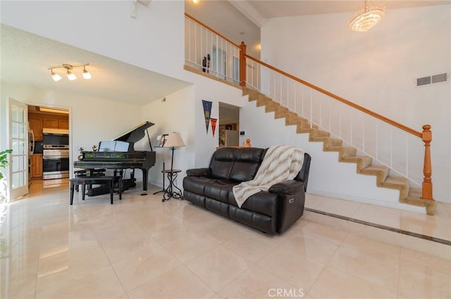 living room with a high ceiling, light tile patterned floors, stairway, and visible vents