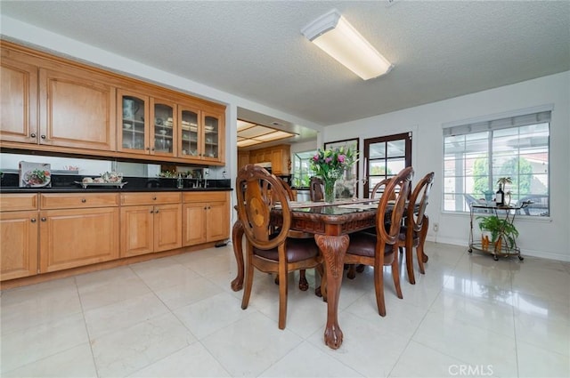 dining room with baseboards, a textured ceiling, and light tile patterned floors