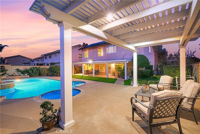 pool at dusk with fence, a pool with connected hot tub, a pergola, and a patio area