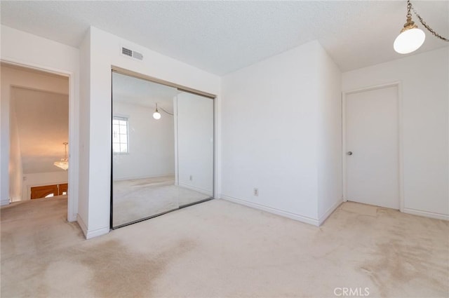 unfurnished bedroom with a closet, visible vents, a chandelier, and carpet