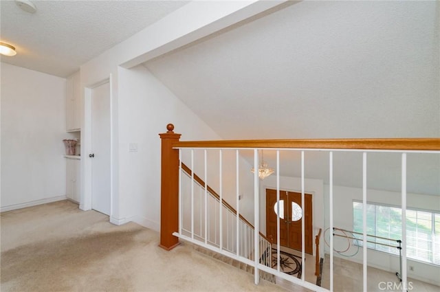 staircase featuring baseboards, carpet flooring, and a textured ceiling