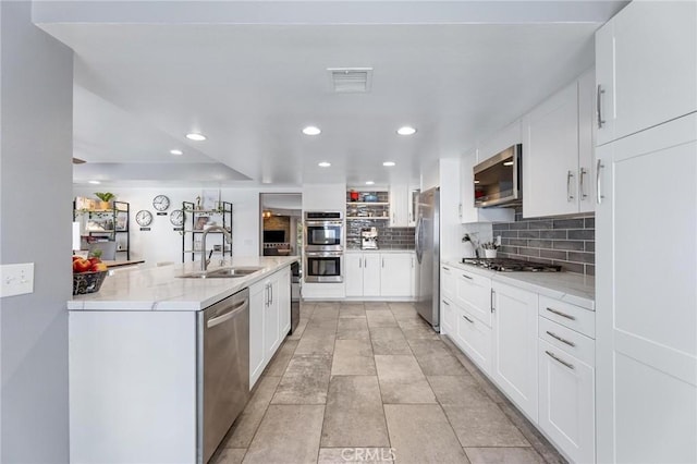 23163 Mulholland Dr Unit 6, Woodland Hills, CA 91364 - kitchen featuring stainless steel appliances, decorative backsplash, white cabinetry, recessed lighting, and light stone counters