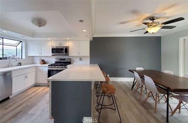 2512 Santa Ana Ave Unit 9, Costa Mesa, CA 92627 - kitchen featuring appliances with stainless steel finishes, a sink, a kitchen bar, crown molding, and backsplash
