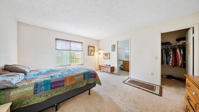 carpeted bedroom with a walk in closet, a closet, a textured ceiling, and ensuite bathroom