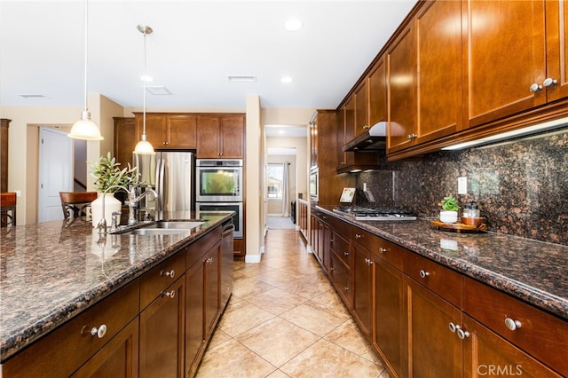 34595 Collier Falls Ct, Temecula, CA 92592 - kitchen with appliances with stainless steel finishes, under cabinet range hood, backsplash, light tile patterned floors, and decorative light fixtures