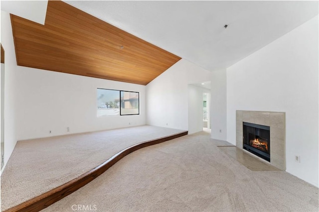 unfurnished living room with wooden ceiling, lofted ceiling, a tile fireplace, and carpet