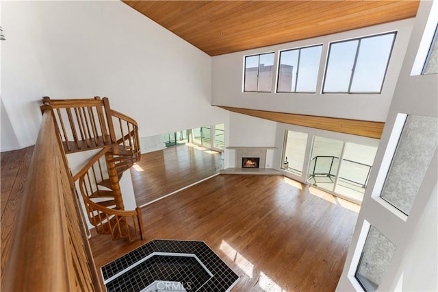 stairs with a towering ceiling, a wealth of natural light, wood finished floors, and wood ceiling